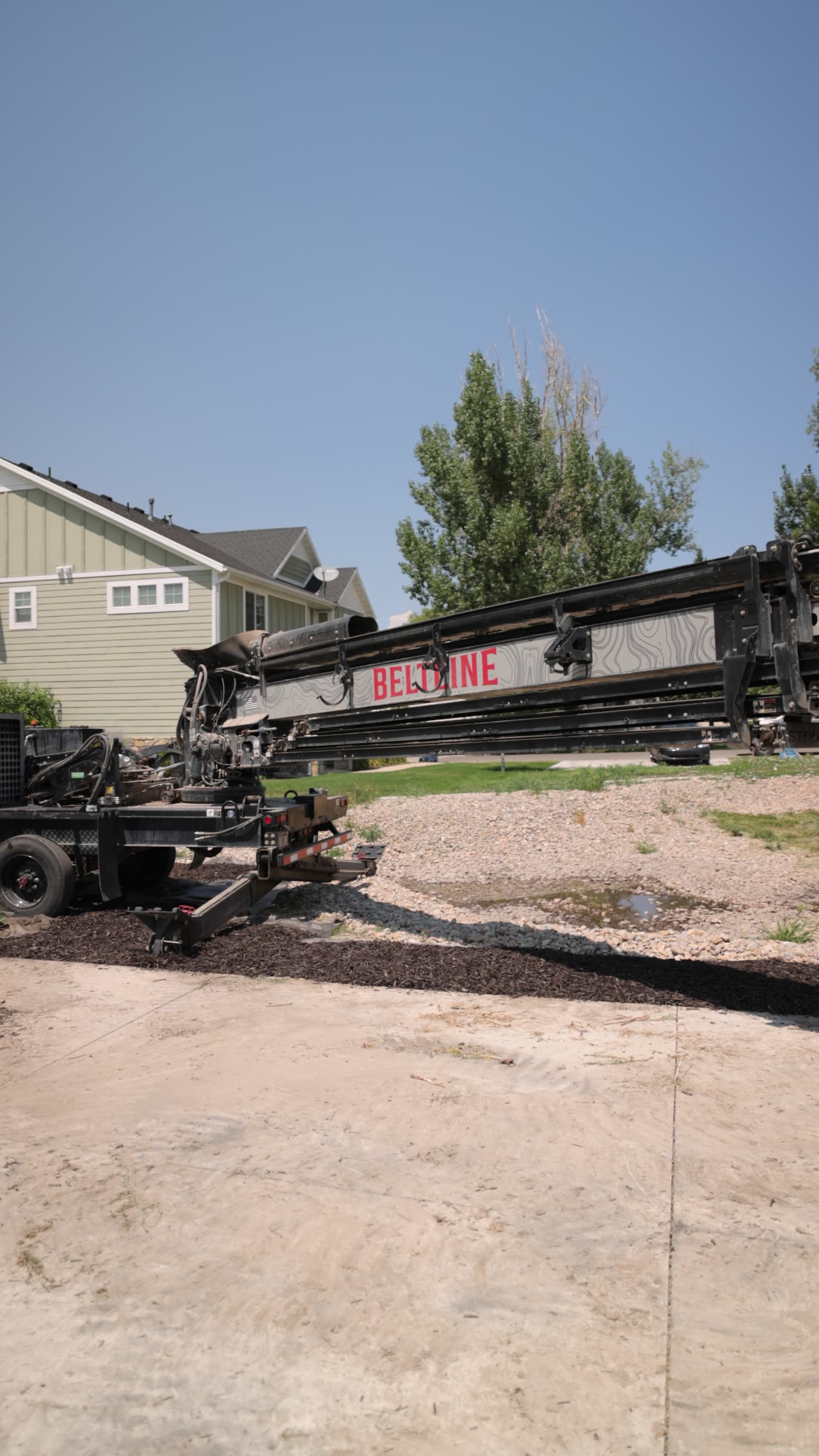 Telescoping conveyor boom extended over a residential job site