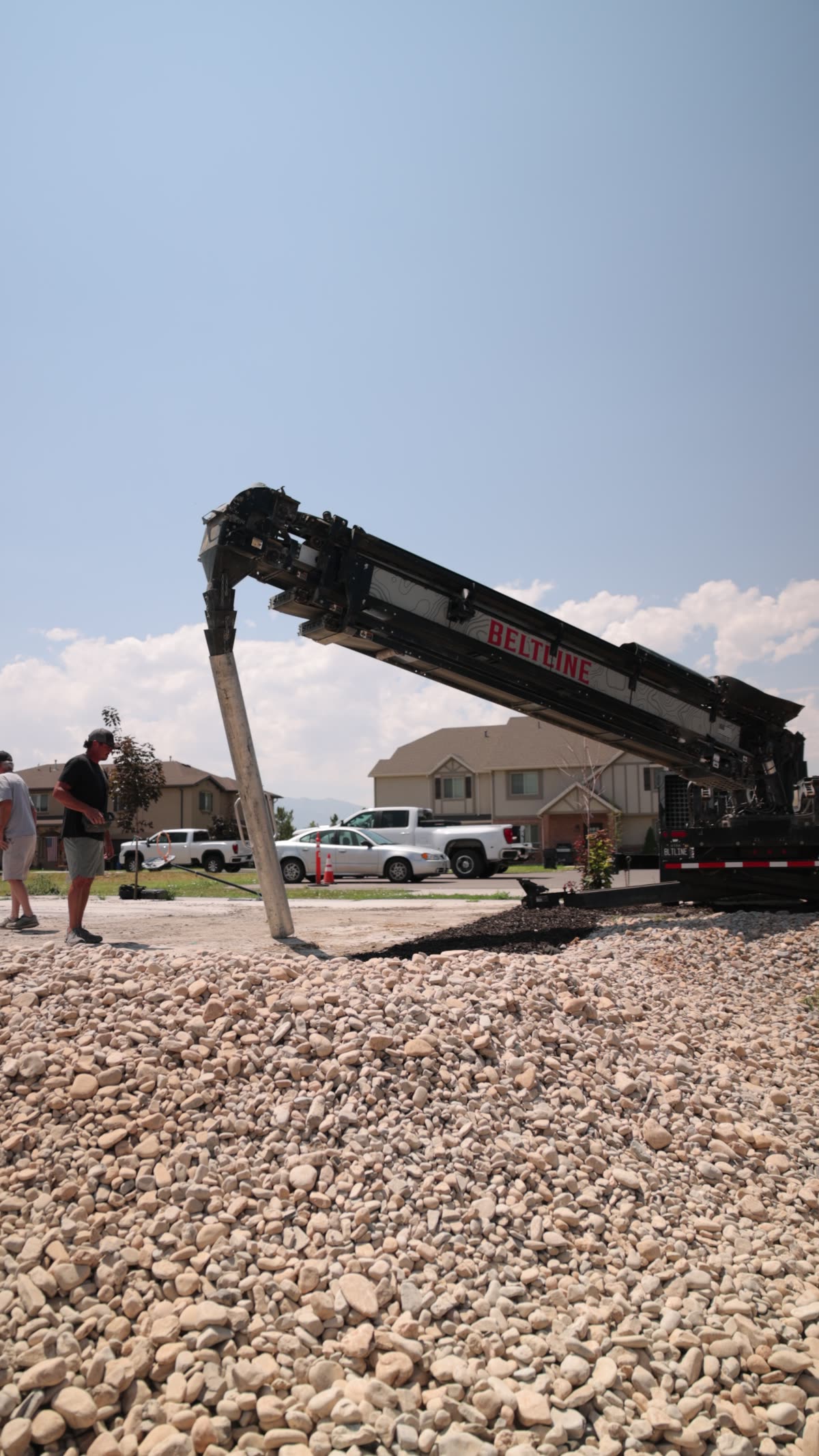 Conveyor boom reaching over a rock-covered lot toward the placement point