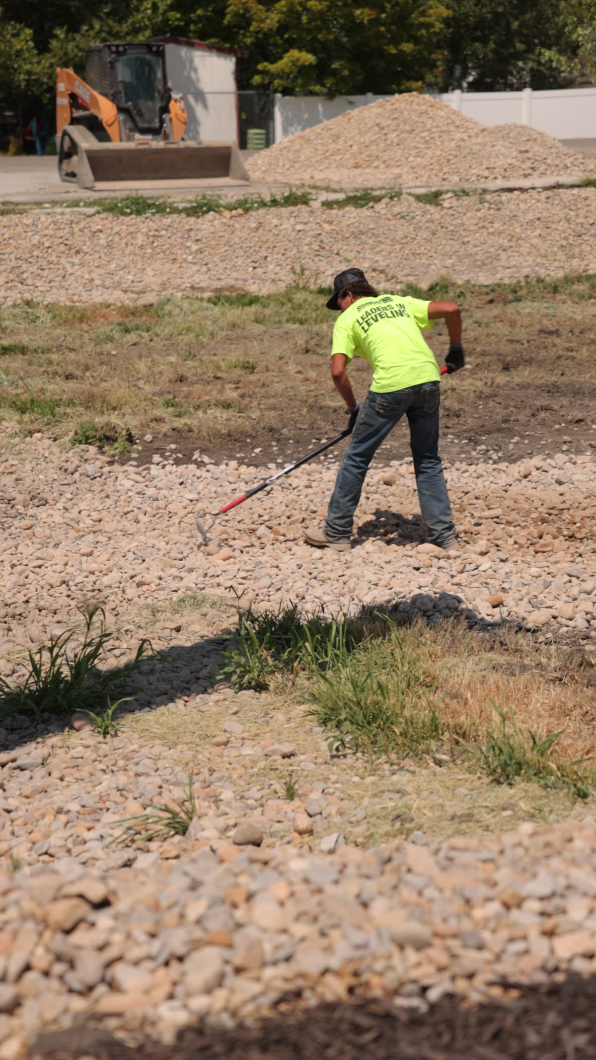 Crew member raking landscape rock placed by the conveyor