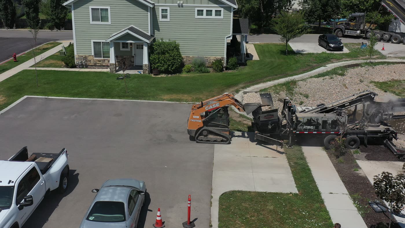 Drone view of a residential job site with the conveyor, skid steer, and trailer on the street