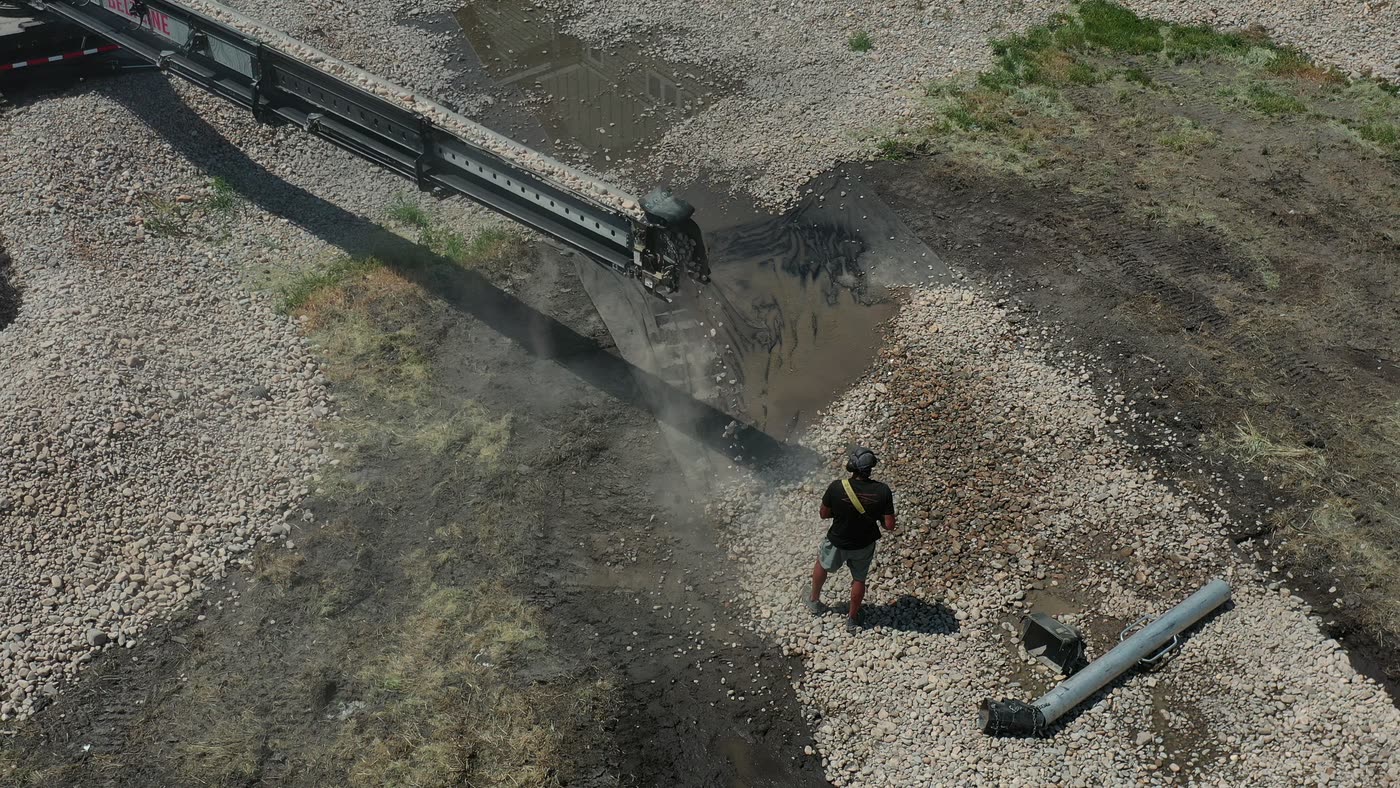 Overhead drone view of the conveyor filling a trench with gravel